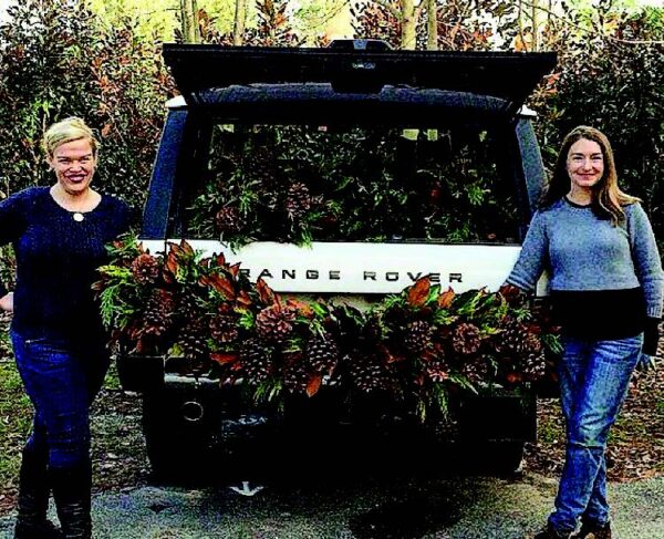 Weston Farms holiday display with two women and floral arrangement on a Range Rover.