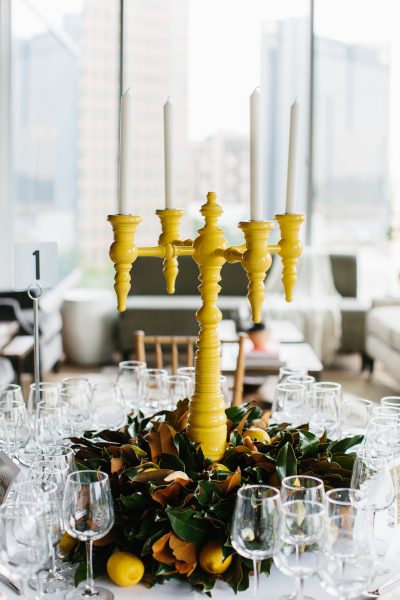 Elegant yellow candelabra centerpiece with greenery and lemons at a Weston Farms event table.