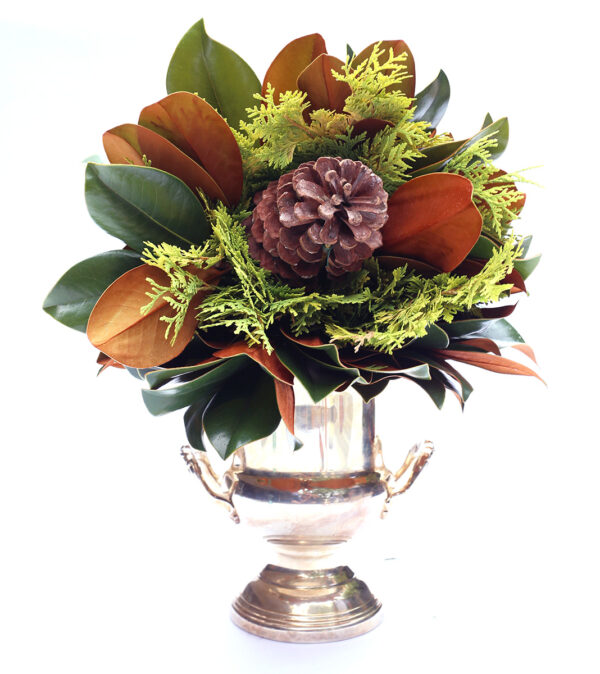 Elegant holiday centerpiece with pine cone and greenery in a silver vase.