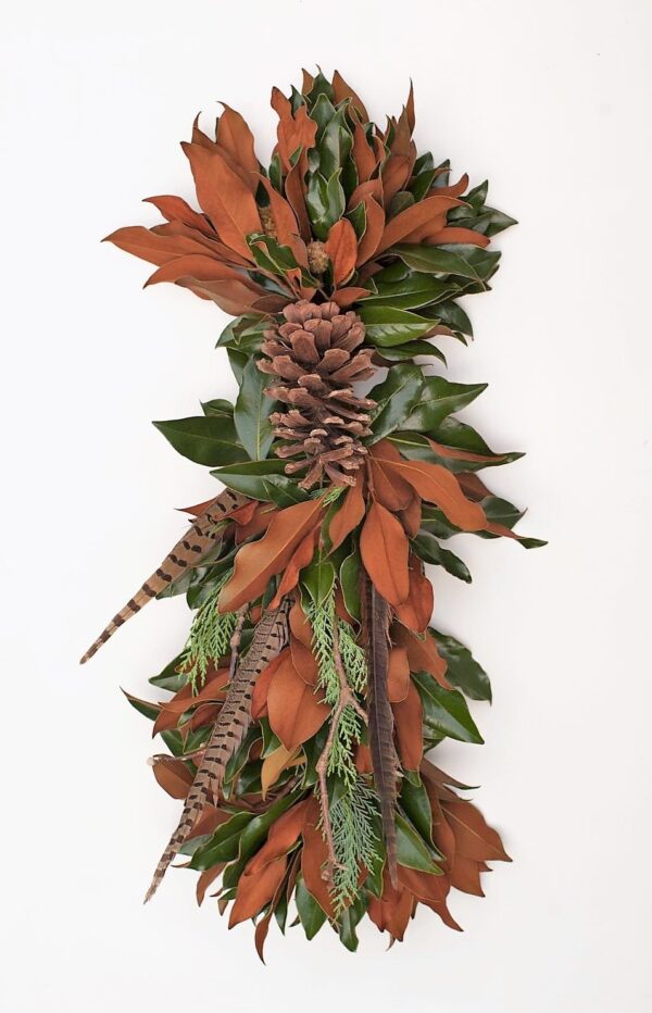 A lush holiday wreath with pinecones, magnolia leaves, and feathers for festive decor.