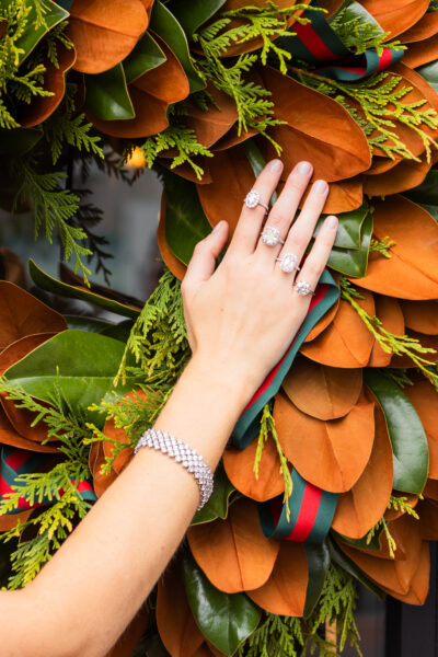 Woman's hand with diamond rings on a holiday wreath.
