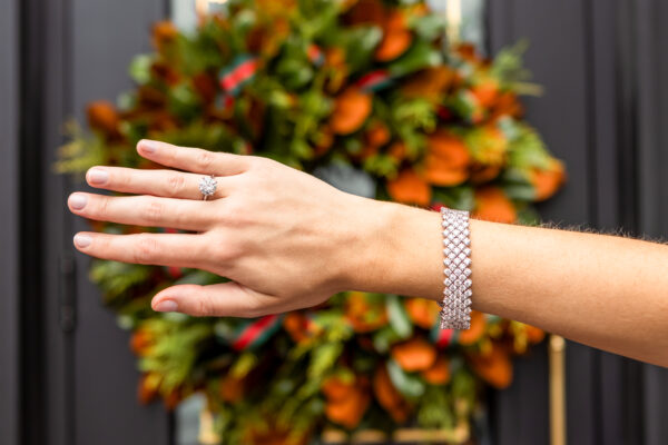 Hand with wedding ring and bracelet in front of autumn wreath at Weston Farms.