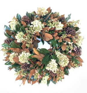 Bright holiday wreath with pinecones, white flowers, and green foliage for festive decoration.