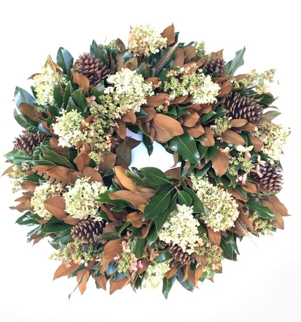 Bright holiday wreath with pinecones, white flowers, and green foliage for festive decoration.