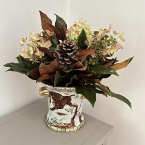 Elegant floral arrangement with pine cone in decorative vase on table.