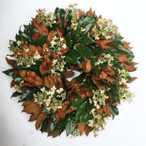 Bright holiday wreath with green and brown foliage, accented by small white flowers, perfect for sea.