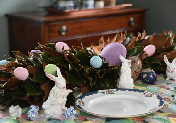 Bright Easter table centerpiece with pastel eggs, bunny figurines, and floral decorations for spring.