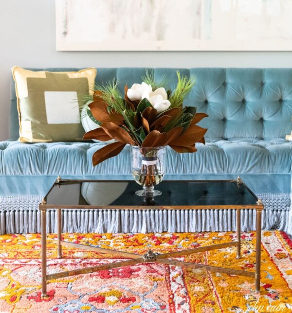 Elegant living room with blue tufted sofa and floral centerpiece.