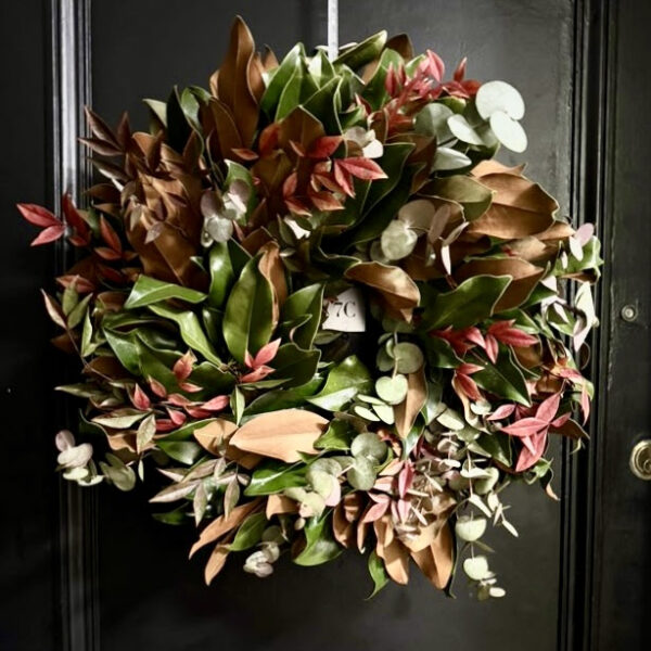 Beautiful holiday wreath with green, red, and brown foliage on a black door.