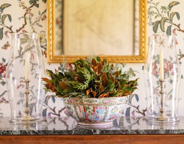 Decorative floral arrangement in a colorful bowl on a marble surface.