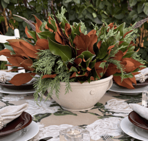 Elegant table centerpiece with lush greenery and brown leaves for Weston Farms event.